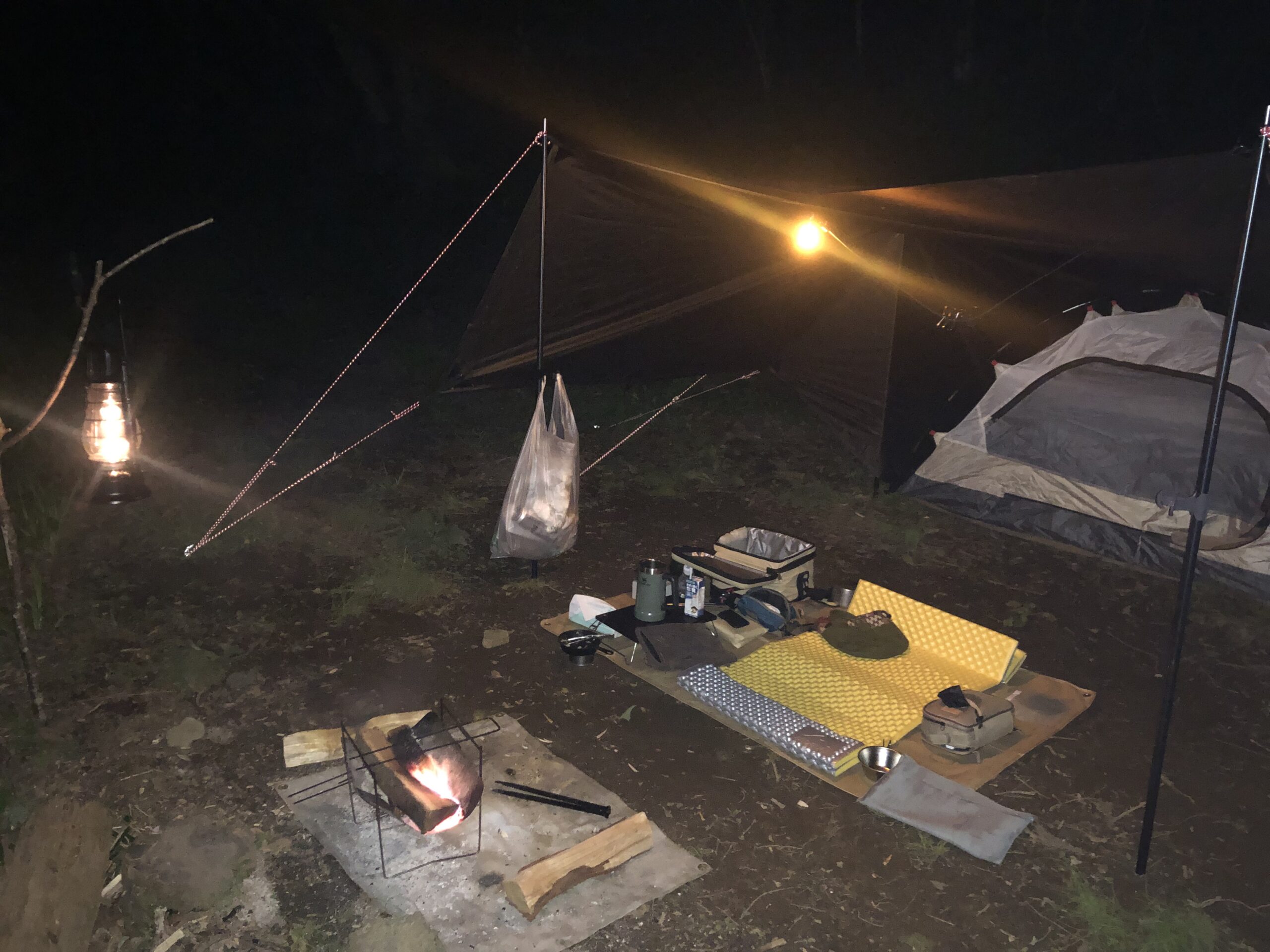 ランタンと焚き火に照らされた筑波高原キャンプ場の夜のタープ泊サイト
